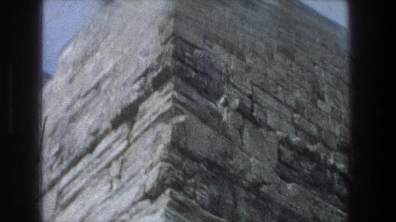 Close view of weathered stone wall against blue sky.