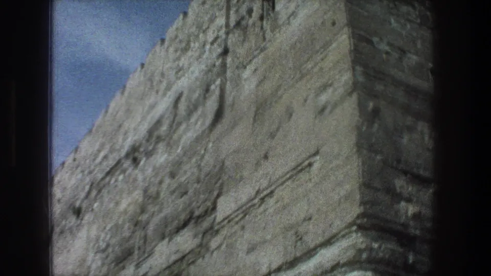 1976 Jerusalem 8mm frame showing a close angled view of weathered stonework under blue sky.