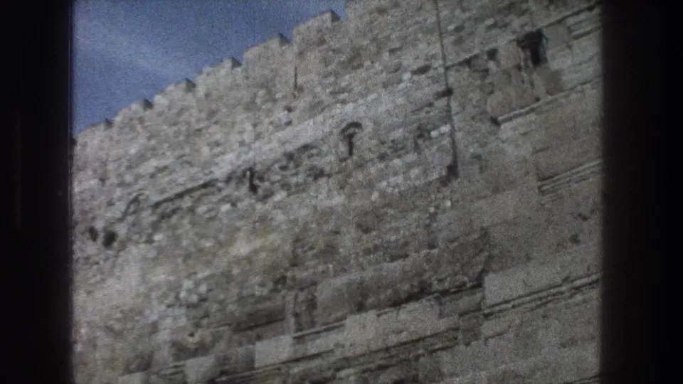 1976 8mm Jerusalem footage showing a close view of weathered crenellated stone walls near the Temple Mount area.