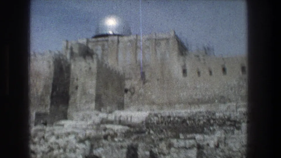 1976 8mm Jerusalem frame with the silver dome and stone walls softened by handheld focus and visible film artifacts.