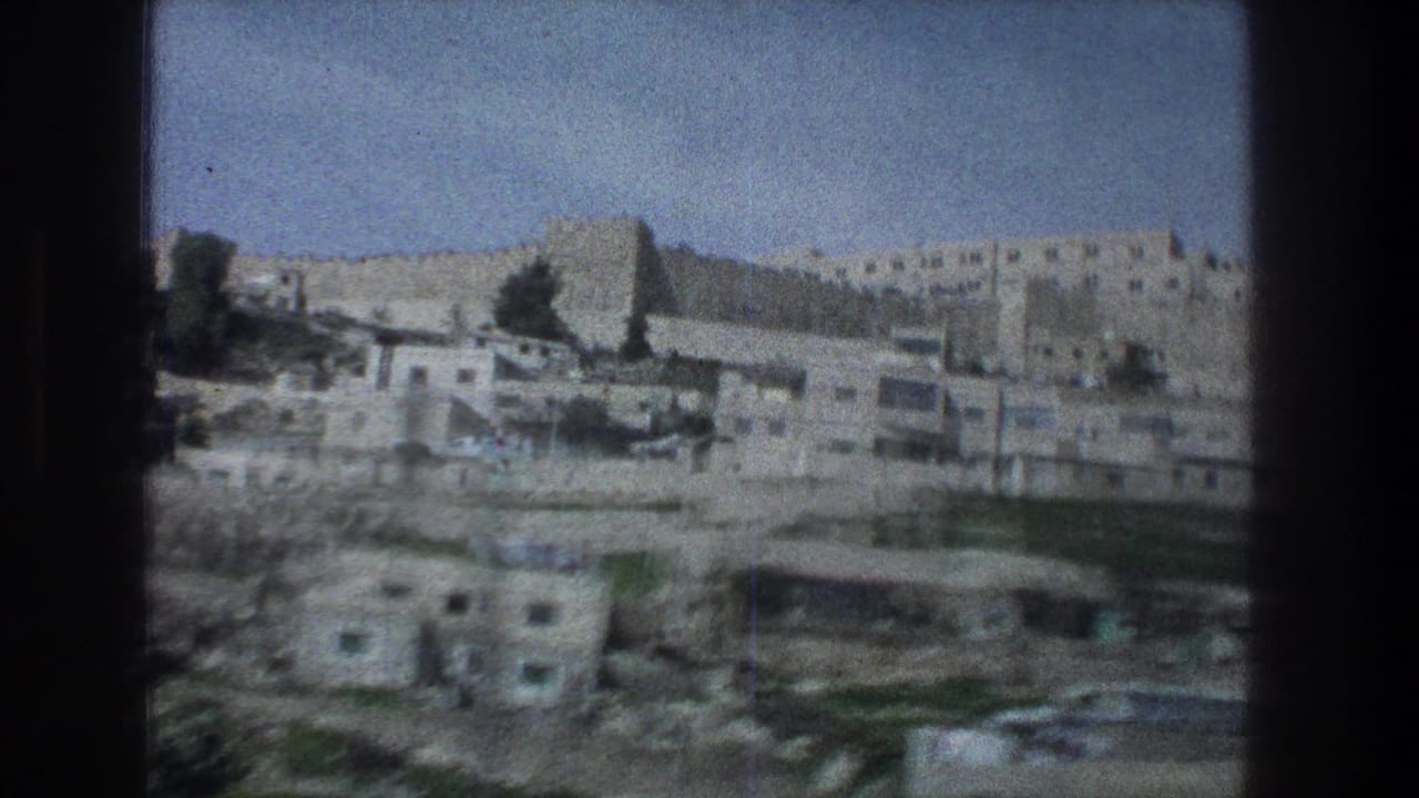 1976 Jerusalem view showing layered stone structures, rectangular windows, trees, and a fortress-like wall on the hill.