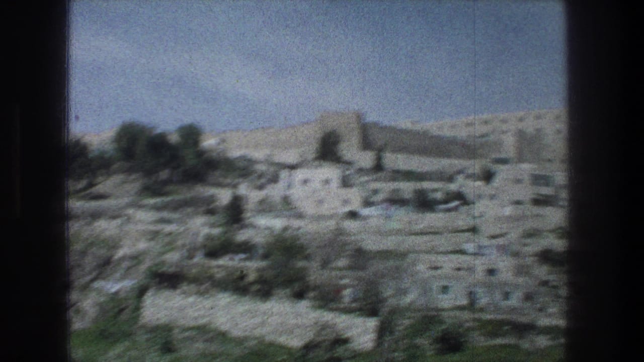 1976 Jerusalem 8mm frame showing a soft, distant view of stone village buildings and hillside terrain.