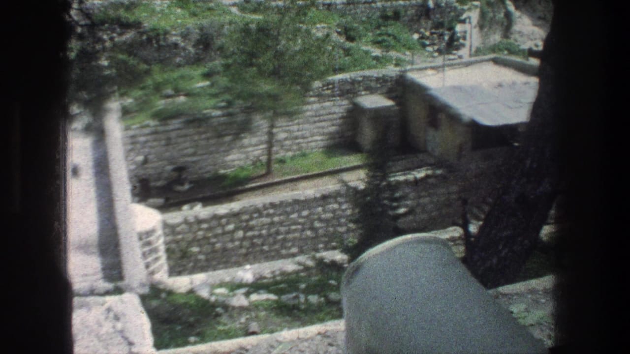 Elevated 1976 Jerusalem view of stone retaining walls, a narrow path, trees, and a small flat-roof building.