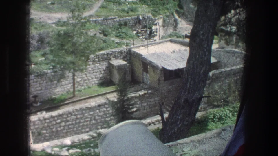 Elevated 1976 Jerusalem view of terraced stone walls, small structures, trees, and hillside paths in soft 8mm color.