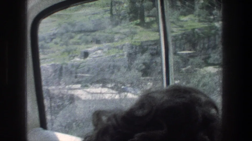 1976 Jerusalem passenger-window view with a partially visible traveler in the foreground and terraced hillside landscape beyond.