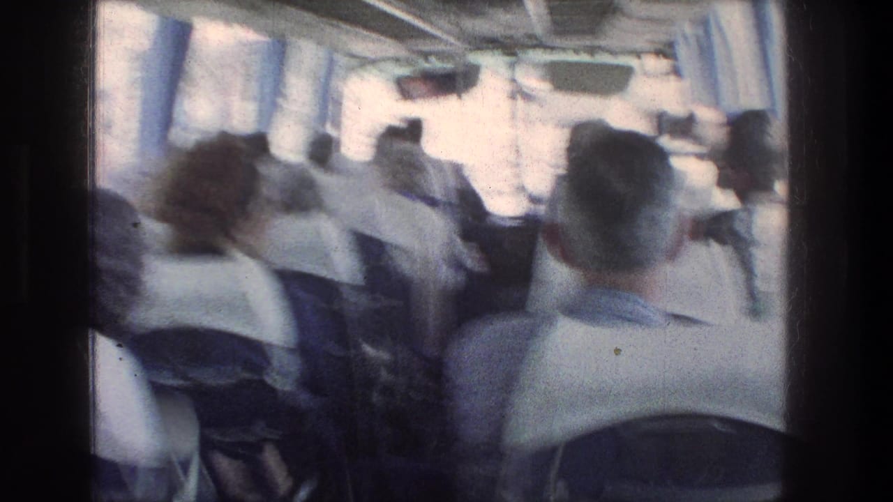 Soft 8mm frame from the Jerusalem bus ride, with seated passengers and blue curtains visible during motion.