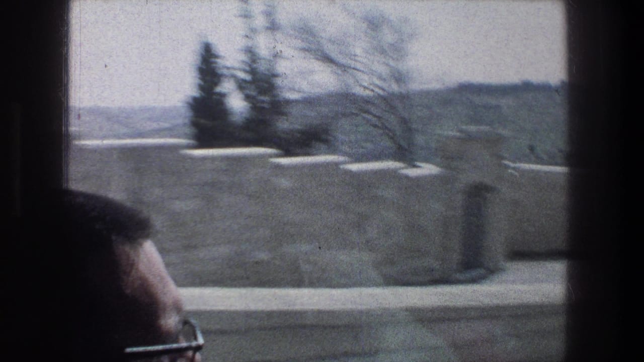 1976 Jerusalem home-movie frame showing a passing view through a vehicle window, pale stone wall, distant hills, and a passenger head in the foreground.