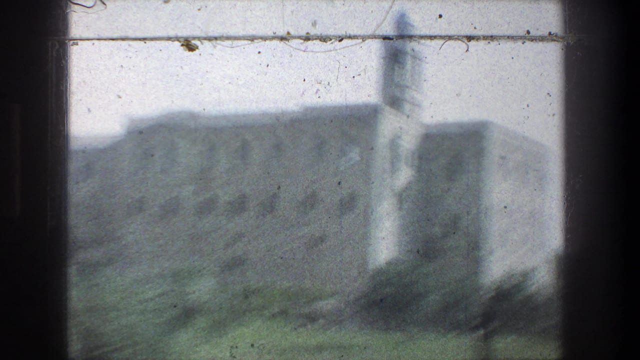 1976 Jerusalem 8mm frame showing a blurred pale stone building and tower glimpsed from a moving vehicle window.