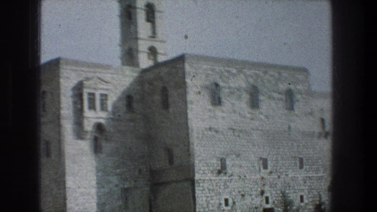 1976 8mm Jerusalem footage showing a pale stone building with arched windows and a bell tower framed by a dark window edge.