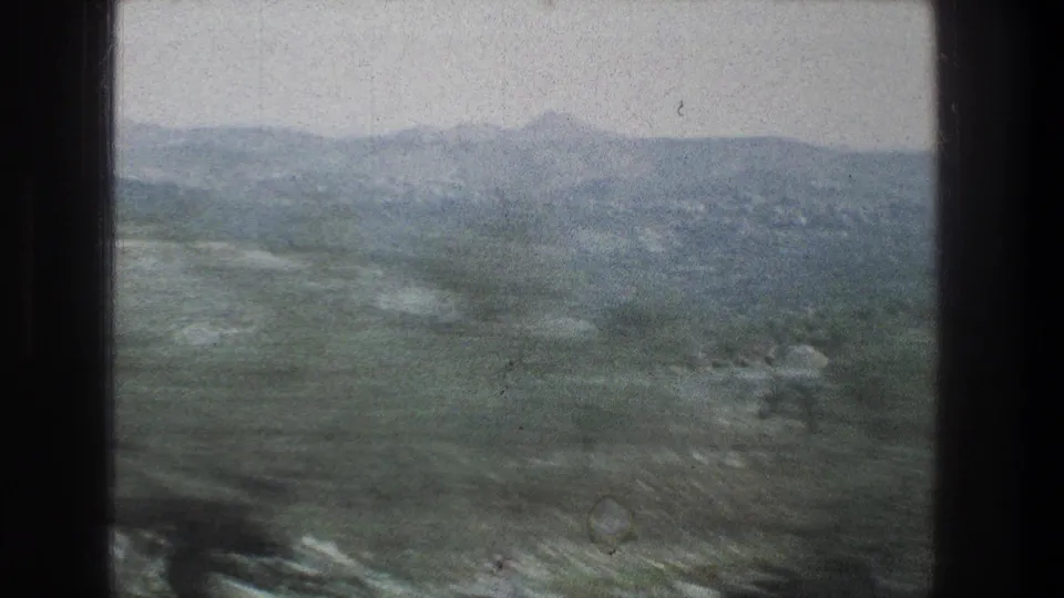 1976 8mm travel view near Jerusalem, Israel, looking past a dark window frame toward hazy hills and scrubby trees.