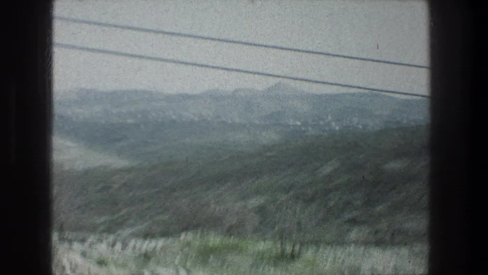 1976 Jerusalem-area travel footage showing a blurred green hillside landscape through a vehicle window with overhead utility wires.