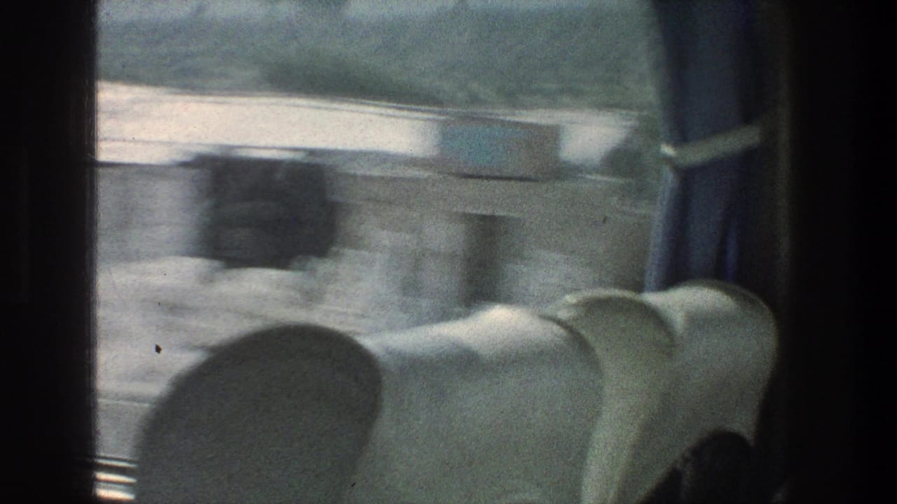 1976 Jerusalem-area home movie frame from inside a moving vehicle, with seats, window framing, and blurred roadside scenery.