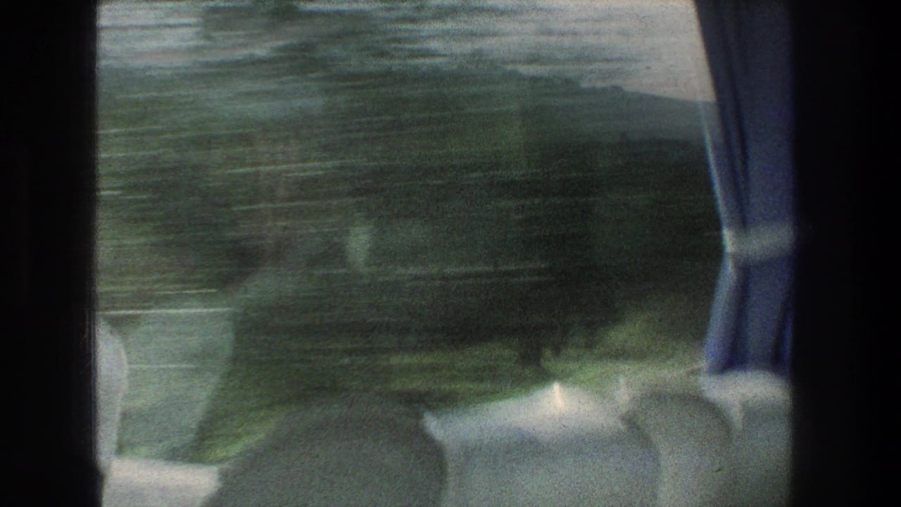 Moving vehicle window view in 1976 Jerusalem-area footage, showing blurred green landscape, seat backs, and curtain detail.
