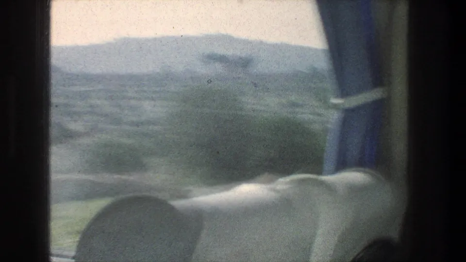 1976 Jerusalem-area travel frame with upholstered seats, blue curtain, and hazy hills seen through the moving window.