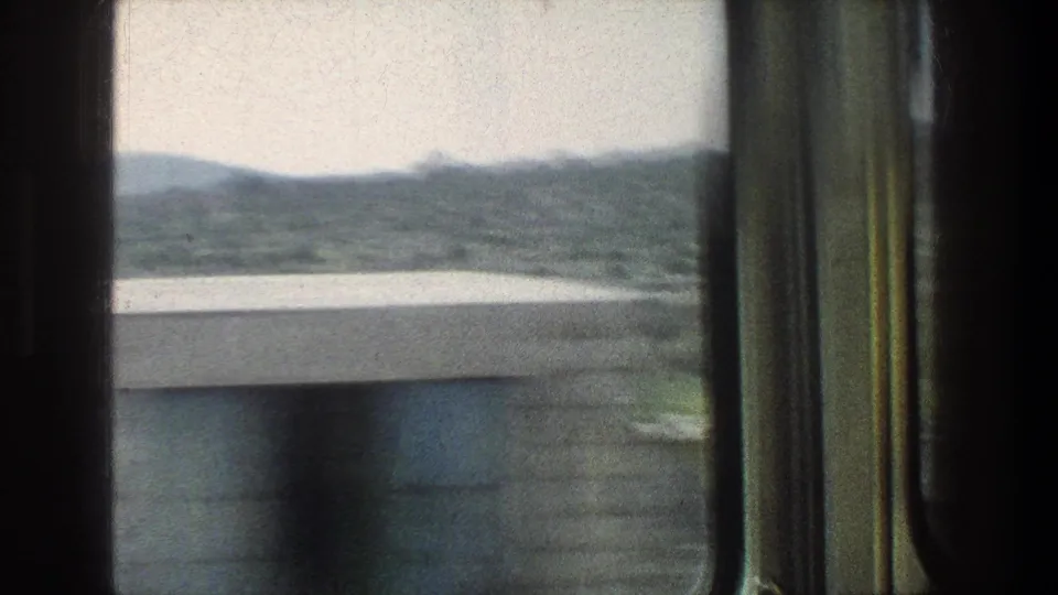 1976 Jerusalem travel footage begins with a moving-window view toward hills and water before the street scene comes into frame.