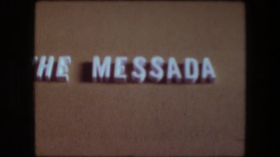 1976 8mm home-movie title card for Messada, with white letters on a brown background and soft film focus.