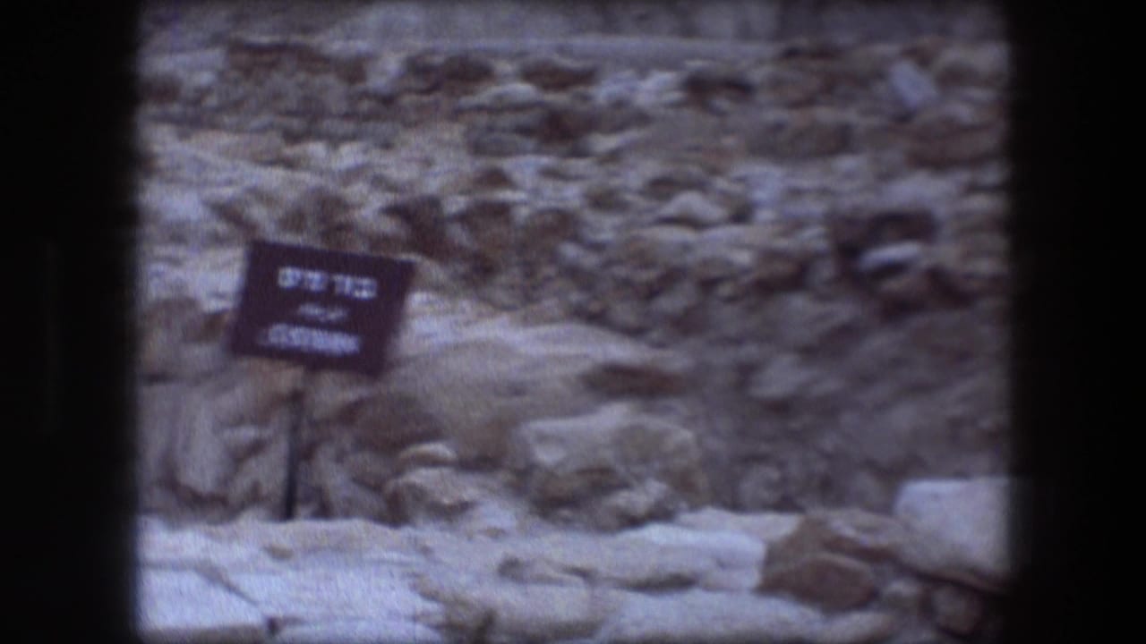 Bilingual Cistern sign beside rough stone ruins and rubble.