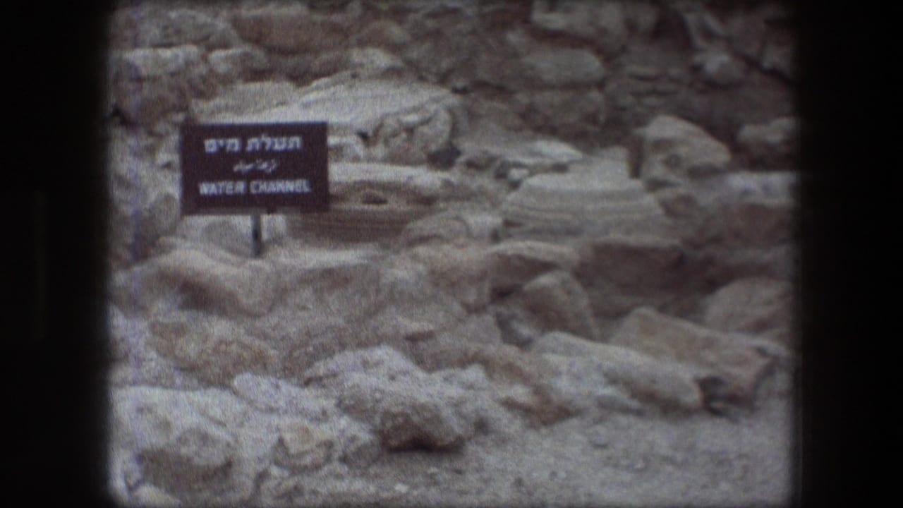 Messada ruins with a bilingual Hebrew and English sign marking the Water Channel among weathered stones.
