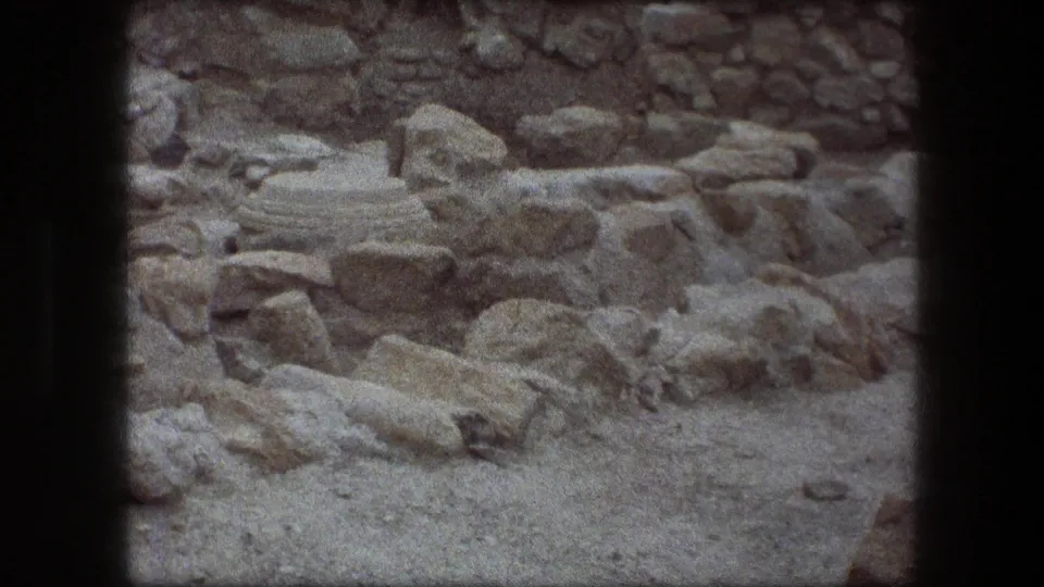 1976 visitor-shot 8mm frame showing weathered stonework and rubble at the Messada archaeological site.