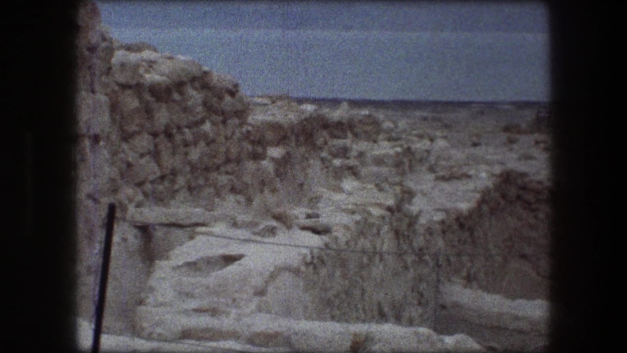 1976 8mm view of weathered stone walls and arid terrain at Messada, Israel, with a distant horizon under a pale sky.