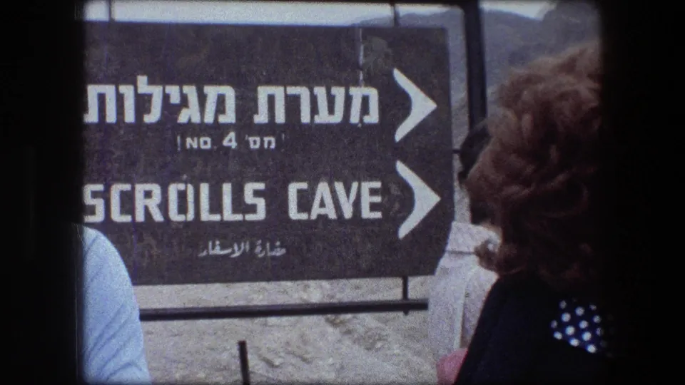 A closer 1976 view of the Scrolls Cave directional sign at Messada, partly blocked by tourists in period clothing.