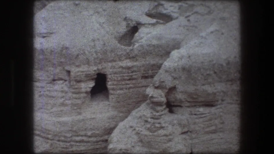 Soft 8mm frame from Messada, Israel, showing eroded rock, a dark opening, and visible film-strip separation.