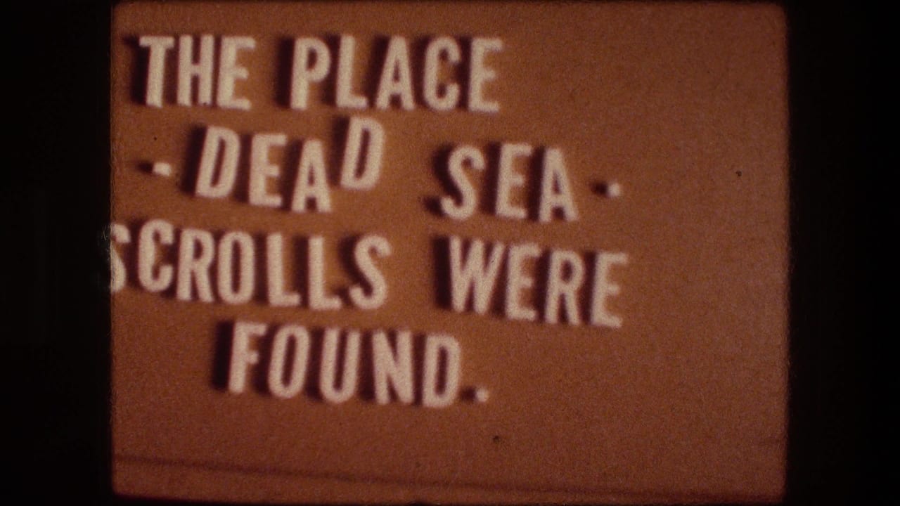 1976 Israel home-movie title card with white lettering reading that the Dead Sea Scrolls were found at the place being introduced.