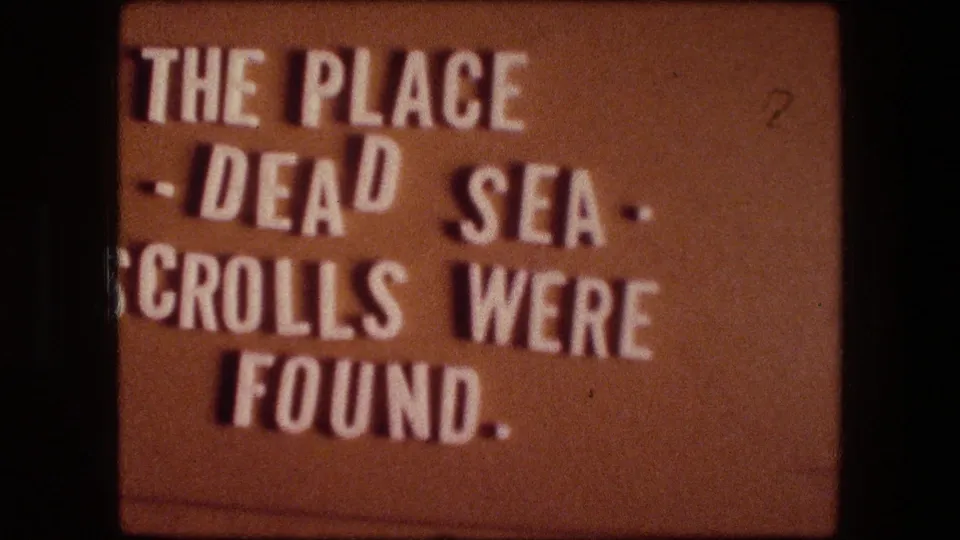 1970s 8mm title card from the Messada, Israel reel, with cropped white text referring to the Dead Sea Scrolls.