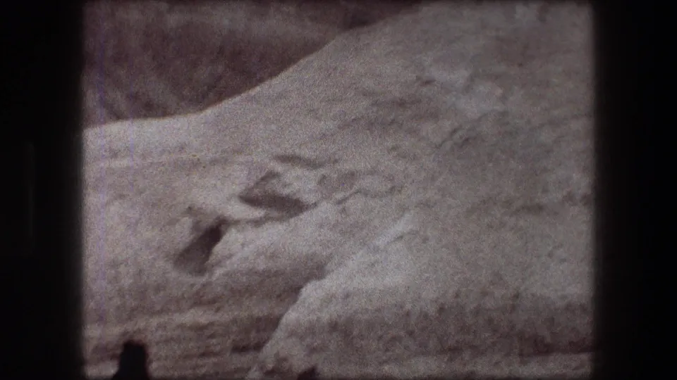 1976 8mm view of a rocky Messada desert hillside with a dark cave-like opening and eroded stone surfaces.