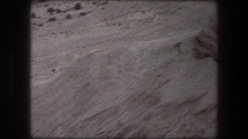 1976 8mm view from Messada, Israel, showing pale layered rock, scattered stones, and visible film gate edges.