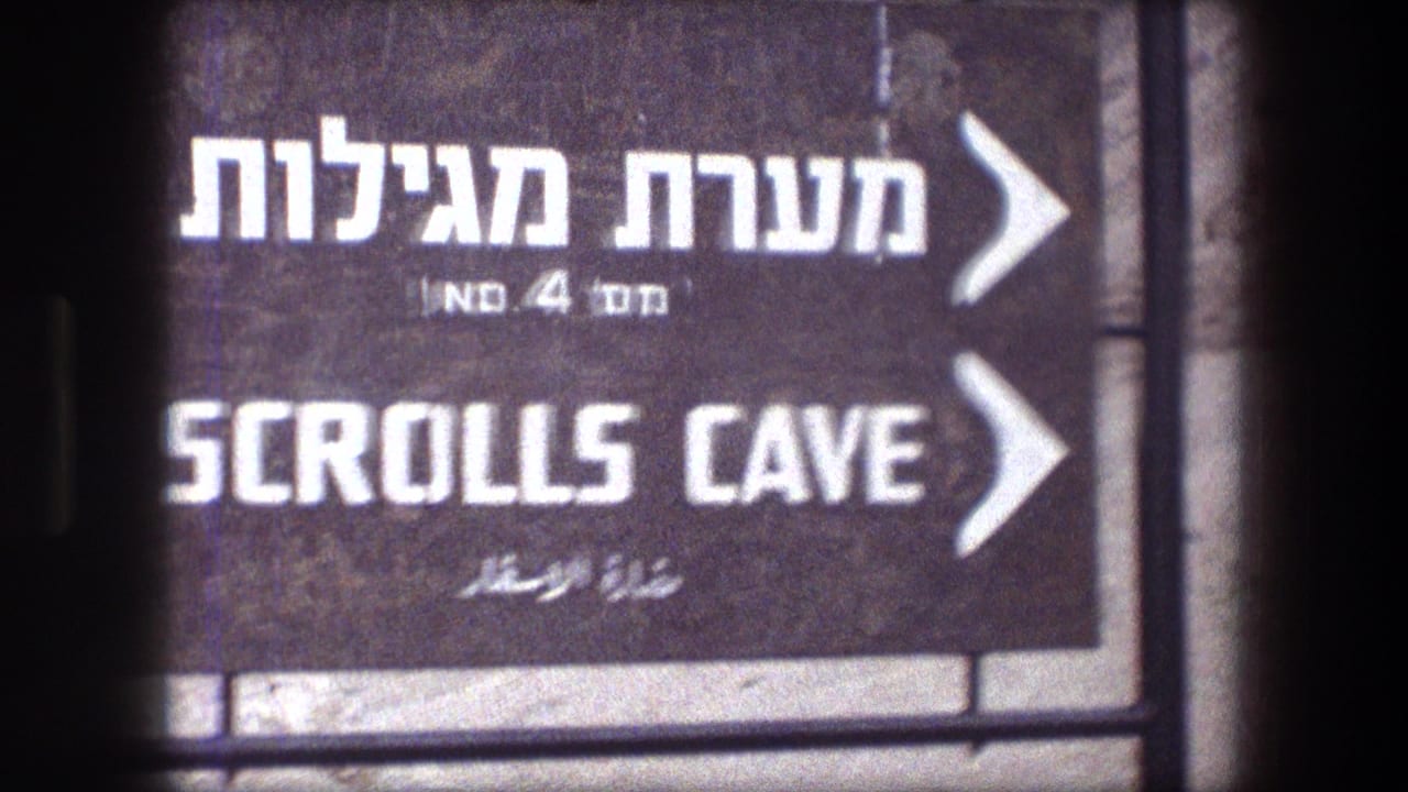 Close 8mm frame of the Masada Scrolls Cave directional sign, showing Hebrew, English, and Arabic text.