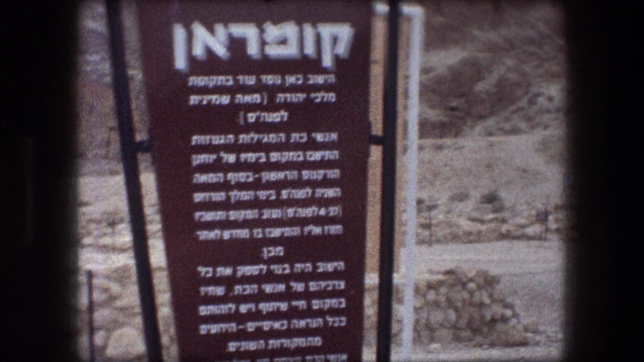 Close view of a brown Hebrew informational sign beside rocky desert terrain.