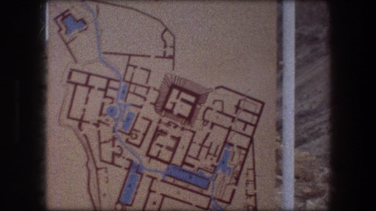 Tan site-plan sign with orange outlines and blue markings, framed by dark film edges.