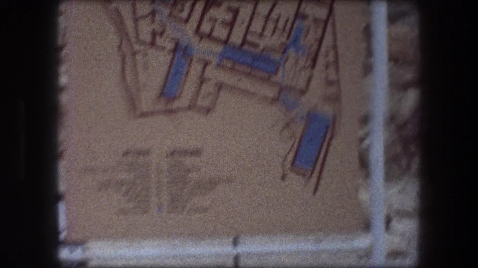 1976 8mm view of the lower Messada map sign, including a blurred legend area beneath orange and blue plan details.