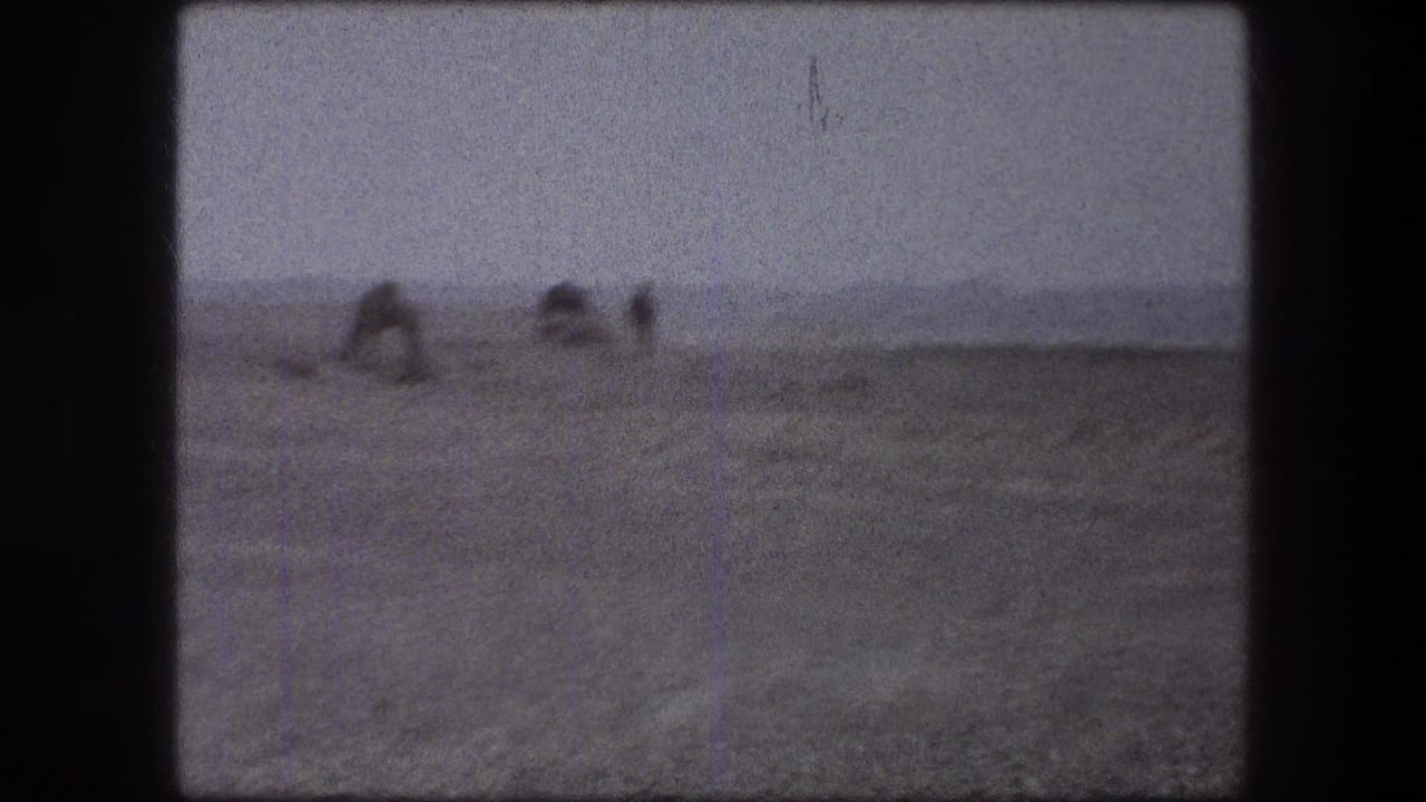 Distant workers bent over in a dusty open field with dark film borders.