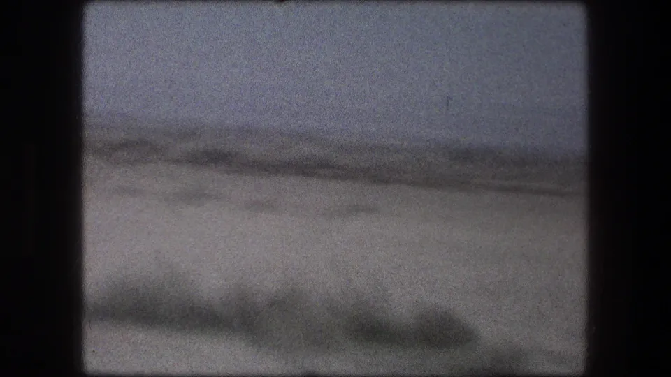 End frame from the 1976 Messada clip, showing mostly open dry ground and a hazy horizon after the workers leave frame.