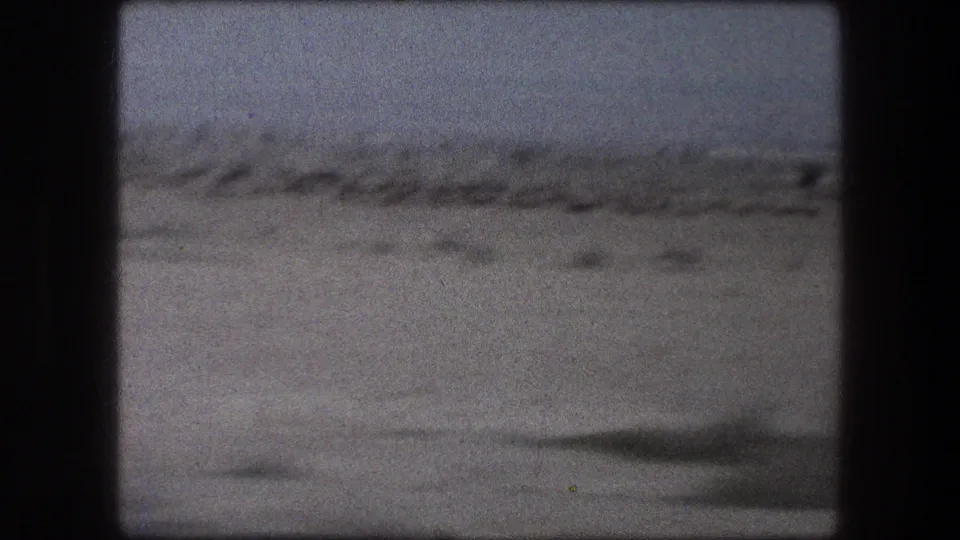1976 8mm Messada, Israel frame showing distant scrub across a flat desert horizon with heavy grain and soft focus.