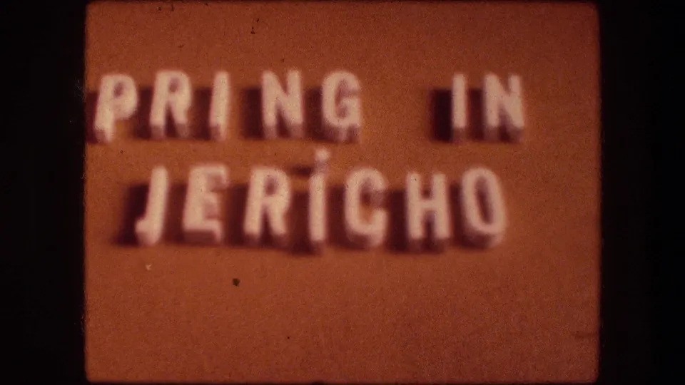 Orange 8mm title card with soft white lettering, partially legible as PRING IN JERICO, likely marking the Jericho travel segment.