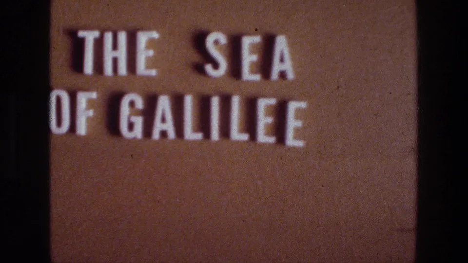 8mm title frame for the Sea of Galilee, with white lettering, warm brown background, grain, and a central dark divider visible.