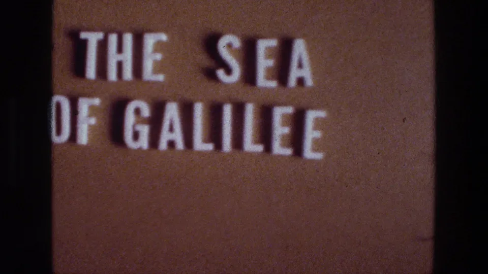 Sea of Galilee title card from a 1976 8mm travel reel, shown softly focused against a warm brown projection surface.