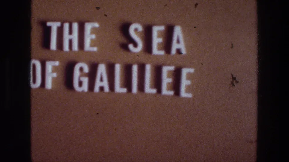 Final sampled frame of the 1976 Sea of Galilee title card, showing white block letters, brown projection surface, and visible film dust.