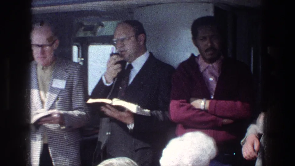 1970s Israel travel footage shows a guide with microphone and book, with nearby passengers listening inside a vehicle.