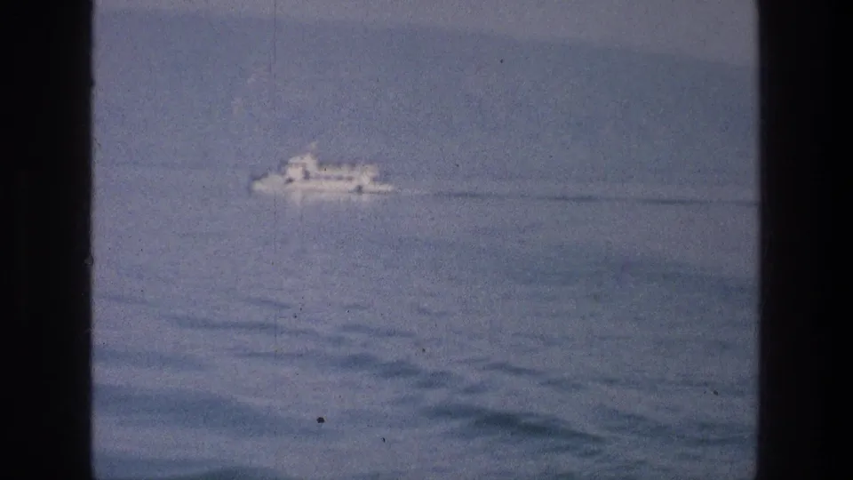 The final 1976 Sea of Galilee frame shows the white boat receding across blue water within dark window-like borders.