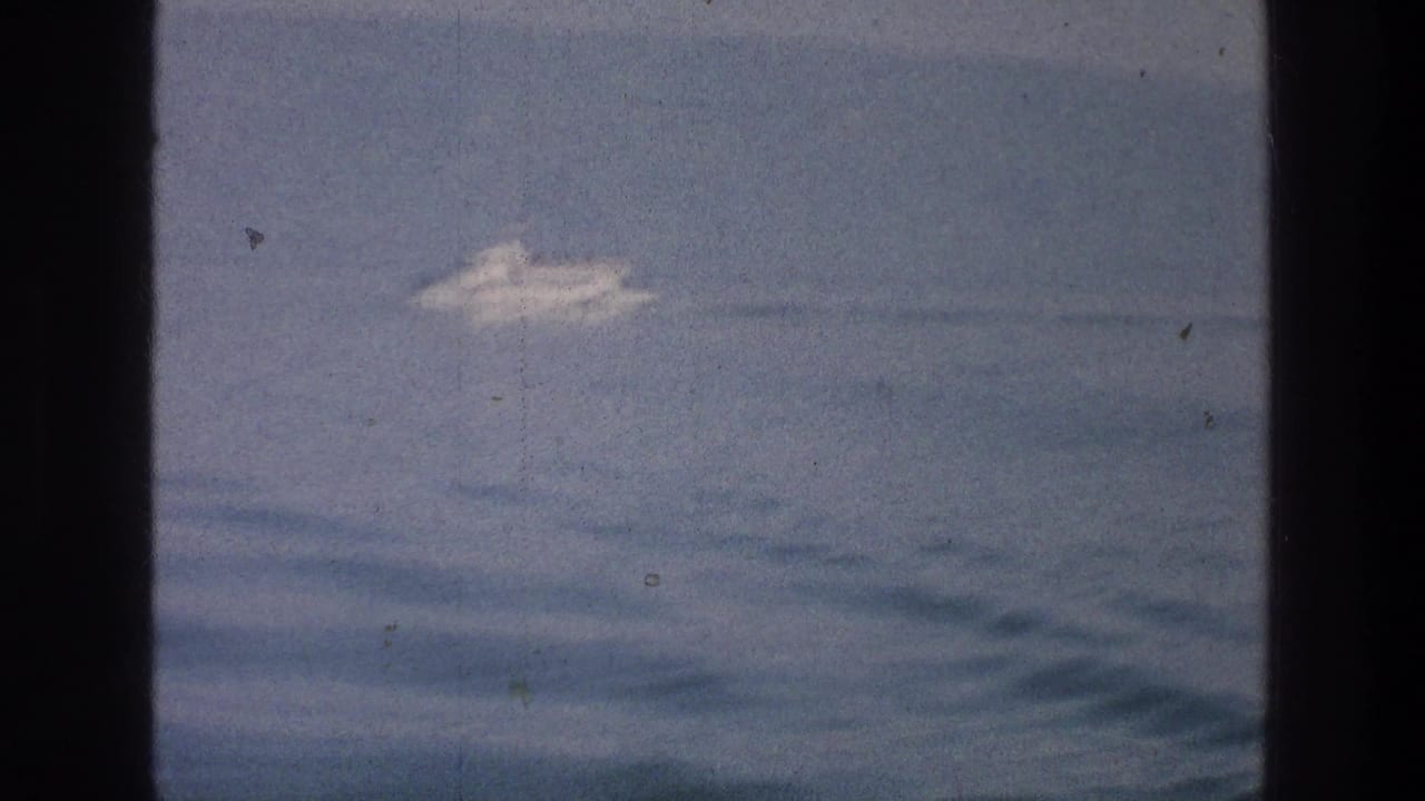 White boat farther across the water, seen through dark vertical film borders.