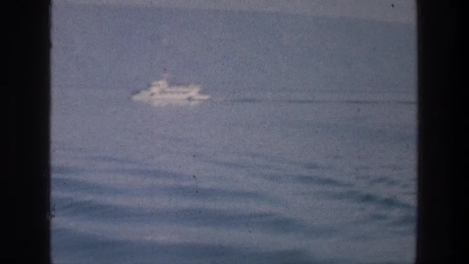 Soft 8mm frame from the Sea of Galilee showing a distant white boat on calm rippled water in 1976.