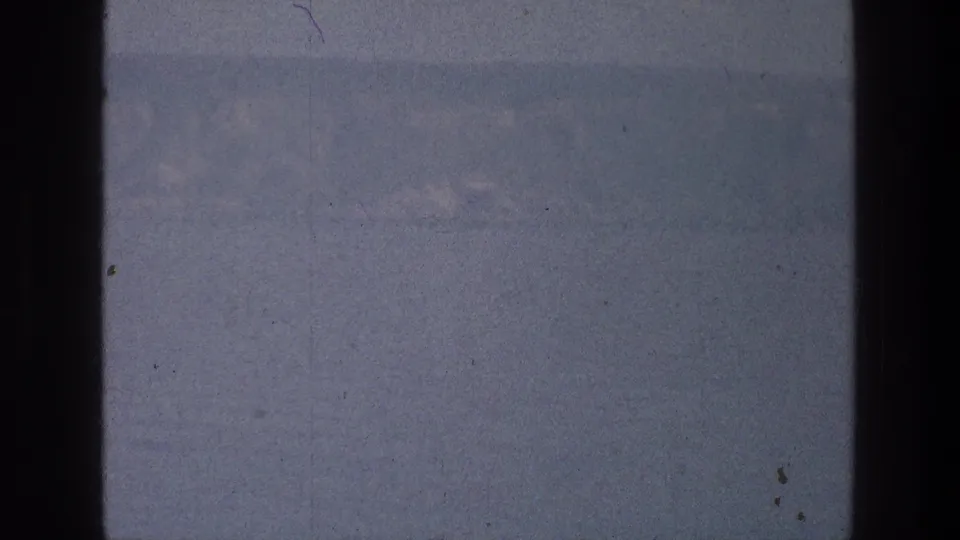 Sea of Galilee landscape on 8mm film, with a hazy mountain ridge partly obscured by a dark vertical gate border.