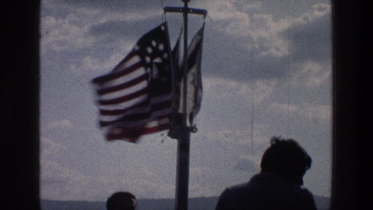 Three flags on a pole seen through dark framing with silhouetted heads below.