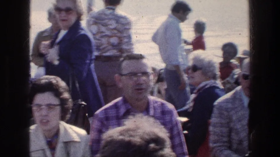 1976 Sea of Galilee boat scene with passengers near the rail, bright water behind them, and dark window framing at the sides.