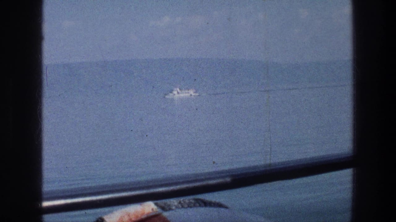 Distant white boat on blue water seen through a dark window frame.