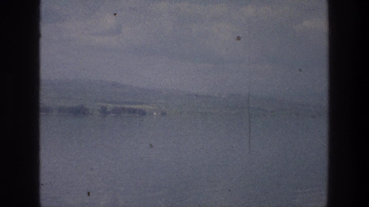 Misty water with a faint shoreline and hills under a pale sky.